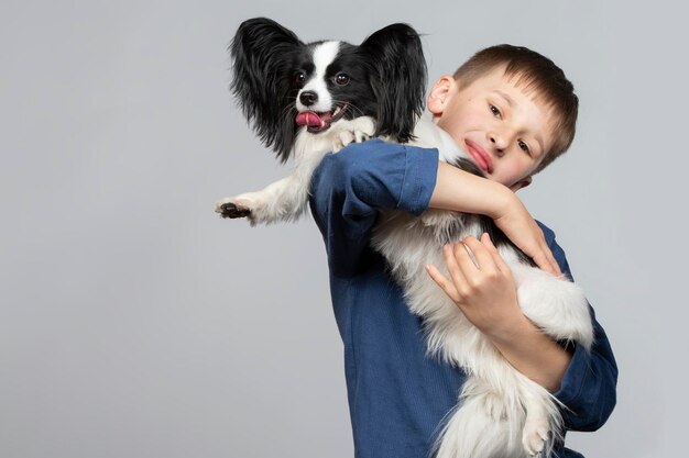 uma criança com um cão da raça papillon no colo posando para uma foto.