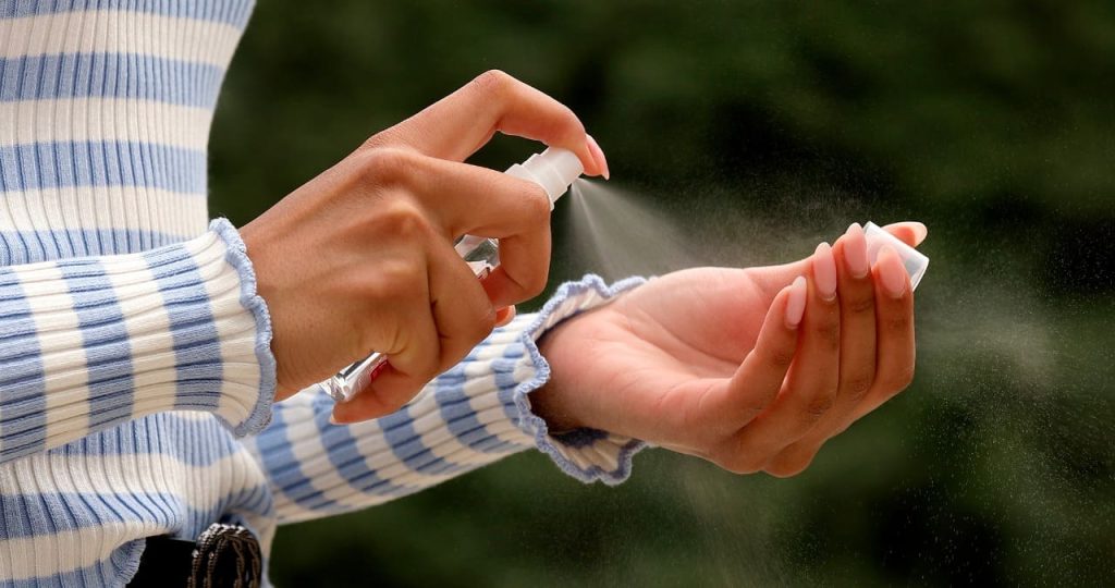 uma moça espirrando spray com repelente para cachorro em suas mãos.