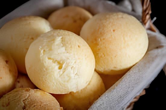 um cesto com vários pão de queijo dentro.
