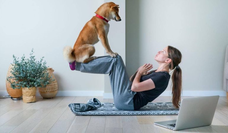 uma mulher fazendo yoga com seu cachorro.