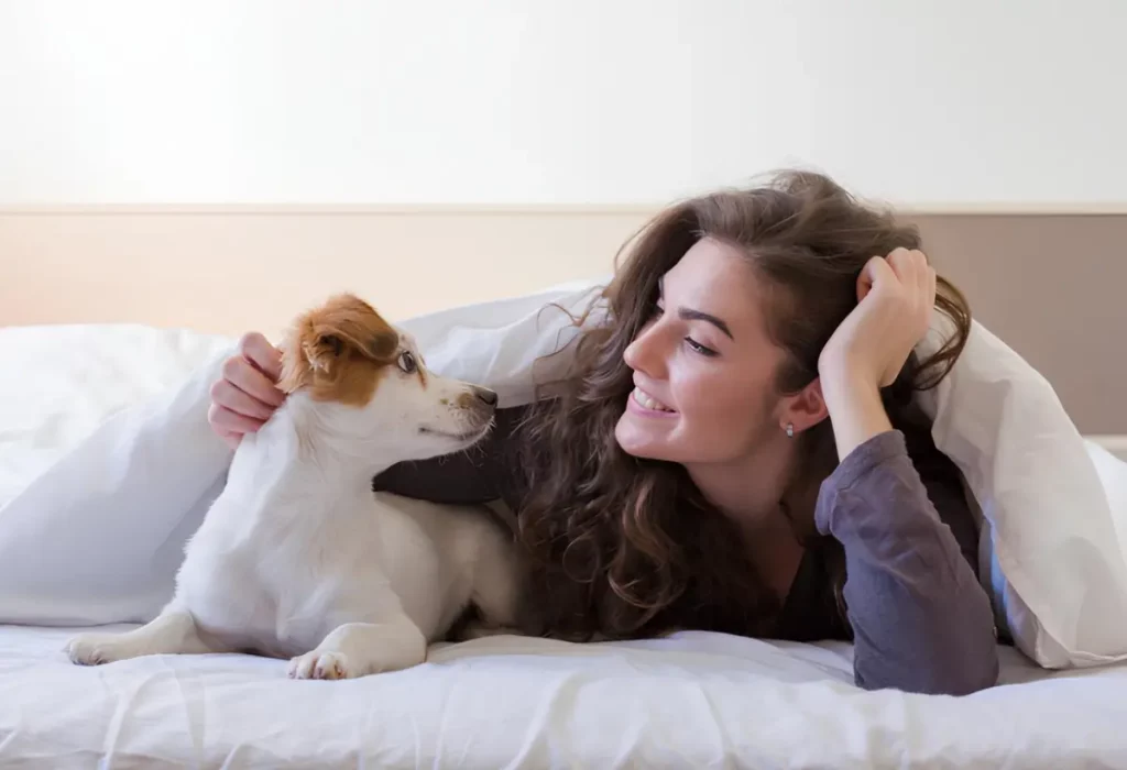 um cachorro com sua tutora na cama .